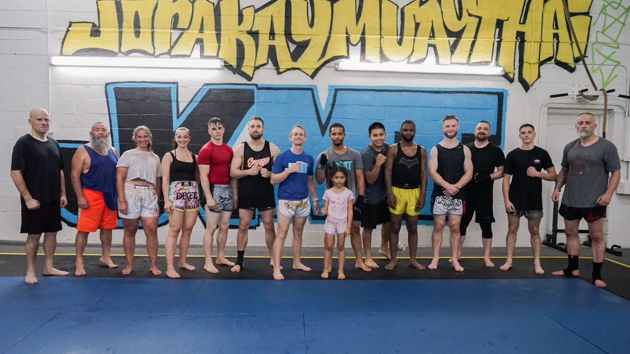 Students and families lined up under the Jorakay Muay Thai mural