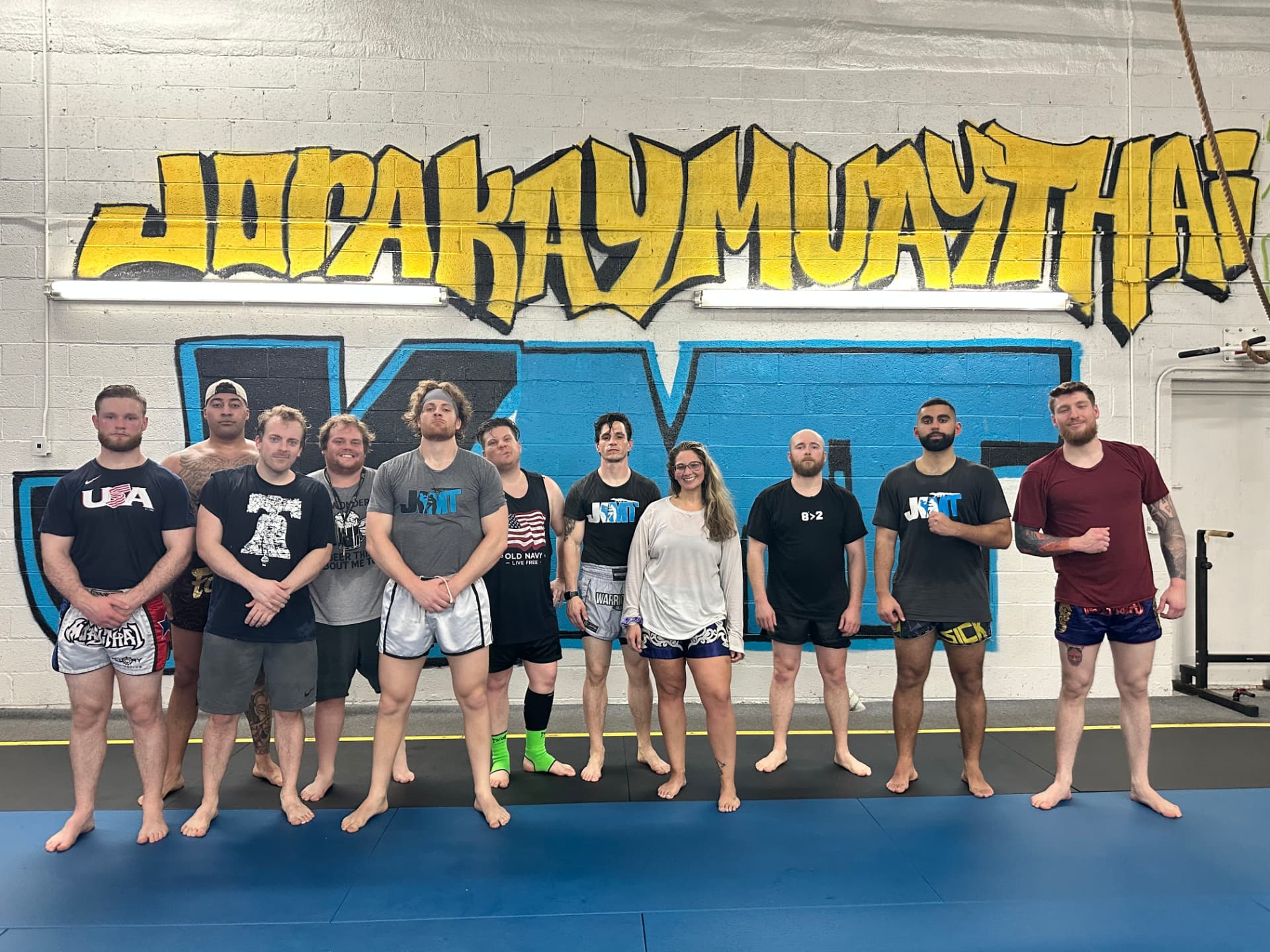 Team posing in front of the Jorakay Muay Thai graffiti wall